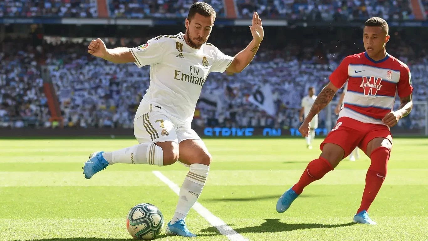 Real Madrid player controlling the ball under pressure from Granada defender during La Liga match — 1xBet Registration